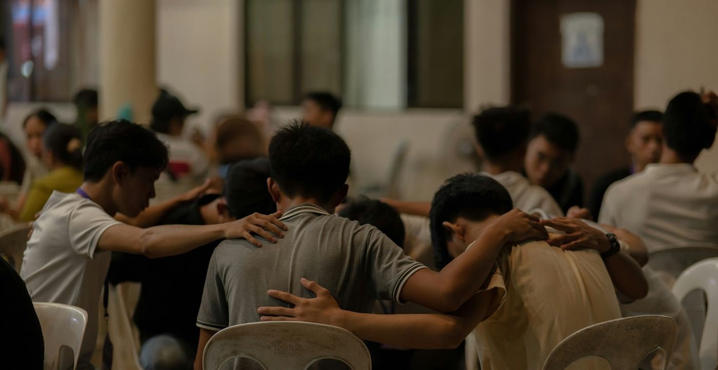 Members of the congregation praying together, hands resting on one another's shoulders